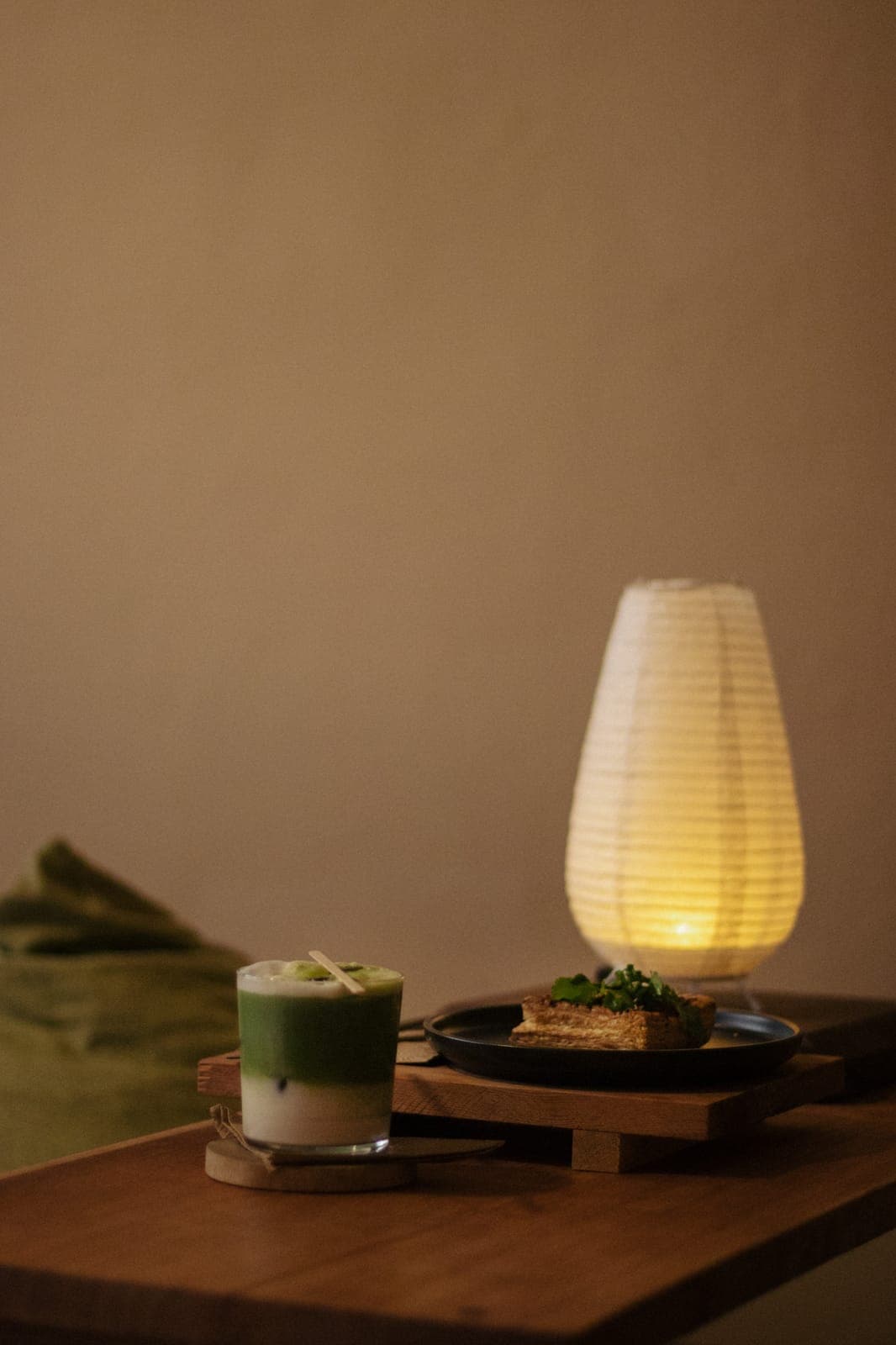 Matcha servido en vaso junto a una lámpara de papel en Deseo Nada Más